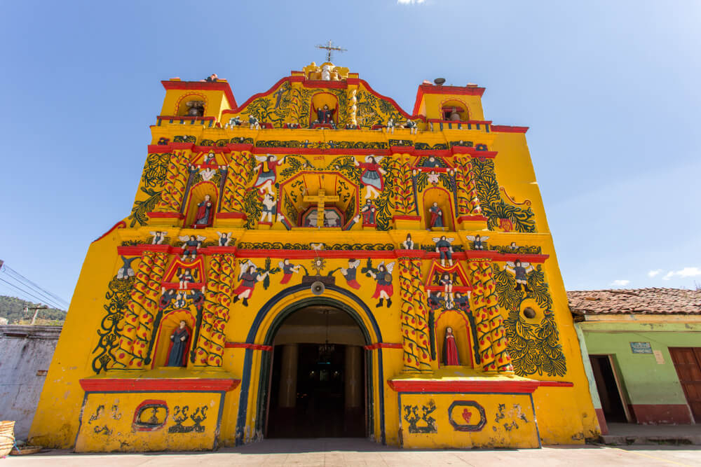 Things to do in Guatemala: A yellow church building covered in green and red ornate painting