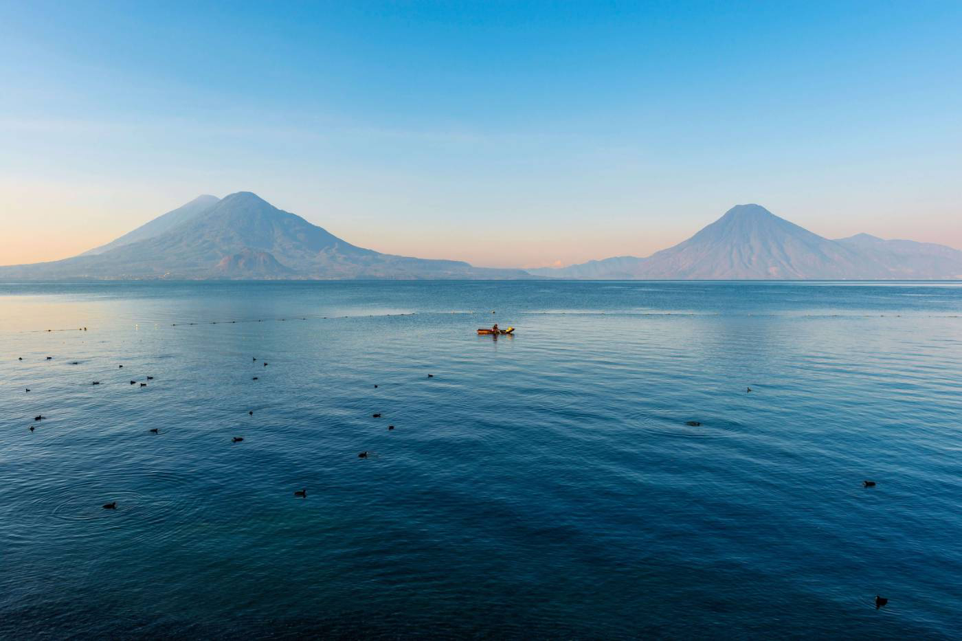 Things to do in Guatemala: the Atitlán lake with a fishing boat sailing on it