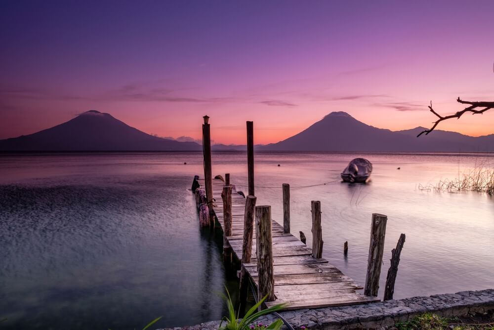 Lake Atitlán: A pier and a sailing boat on Lake Atitlán, Guatemala against a purple sunset