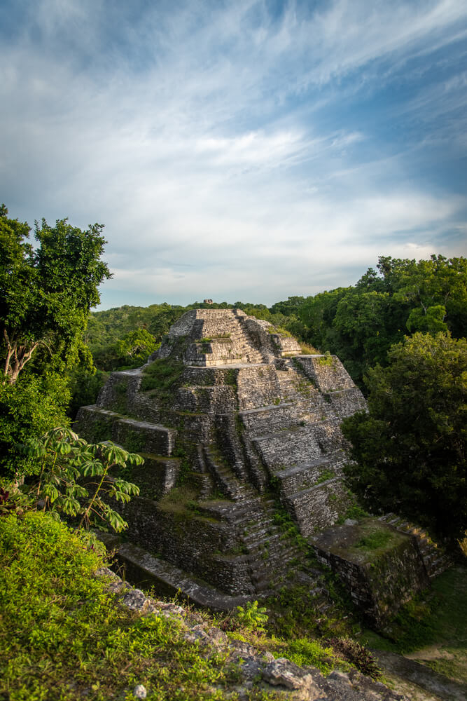 Yaxha: A tall stone pyramid surrounded by trees in the jungle