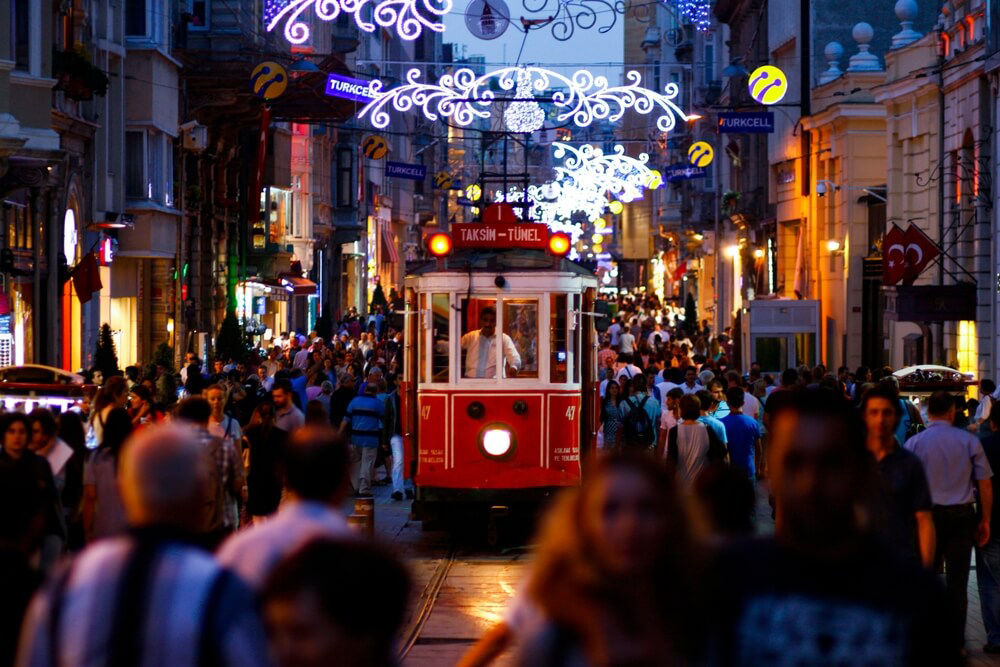 Beyoglu: a busy city street at night full of people and a tram 