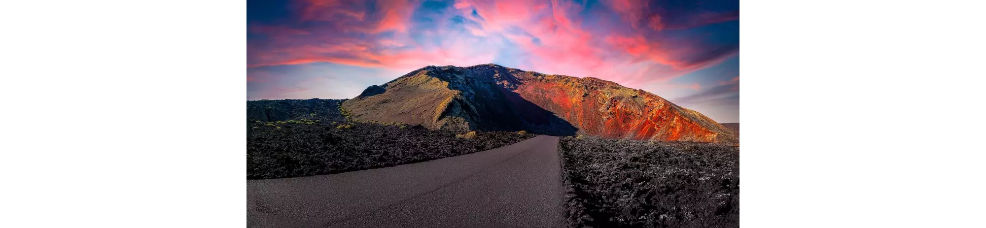 Timanfaya National Park: The sun setting over a black sand road and volcano