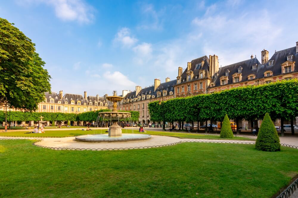 Things to do in Le Marais: A green square with a grand arcade surrounding it
