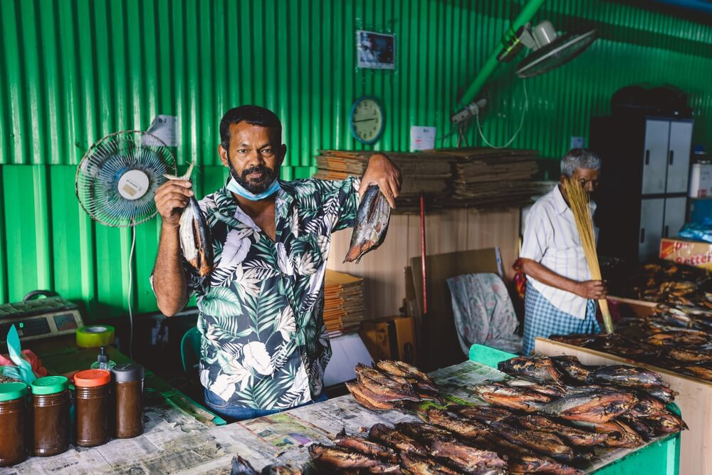 Things to do in Male: A man holding up fish in the Male market