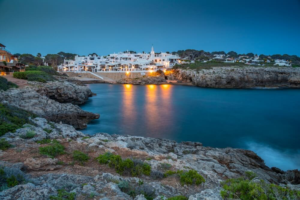 Binibeca Vell: A bay with a white town at sunset