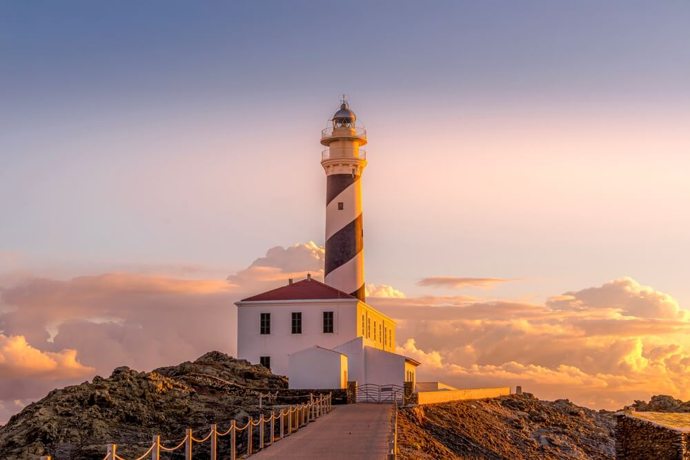 Cap de Favàritx Lighthouse: A red and white striped lighthouse at sunset