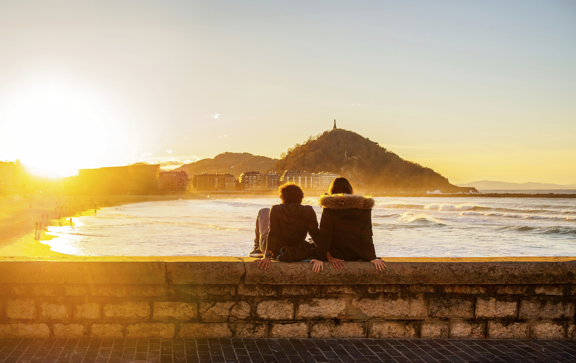 Things to do in San Sebastián: A couple sat on a sea wall looking at the sunset