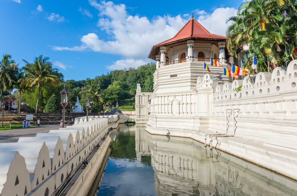 Temple of the Sacred Tooth Relic: A white religious building surrounded by a moat and trees