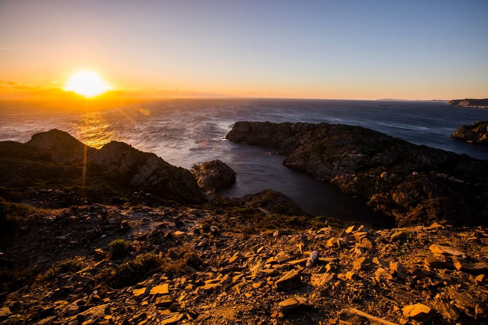Cap de Creus: Black small rocks on a cliff and the ocean at sunset 