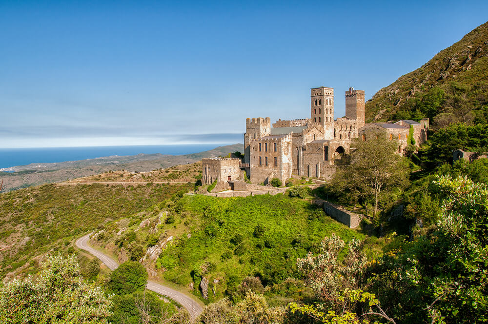 Sant Pere de Rodes: A large stone monastery on top of a tall green hill