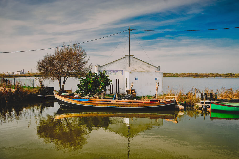 Albufera: A lake and a white building with a fishing boat in front of it