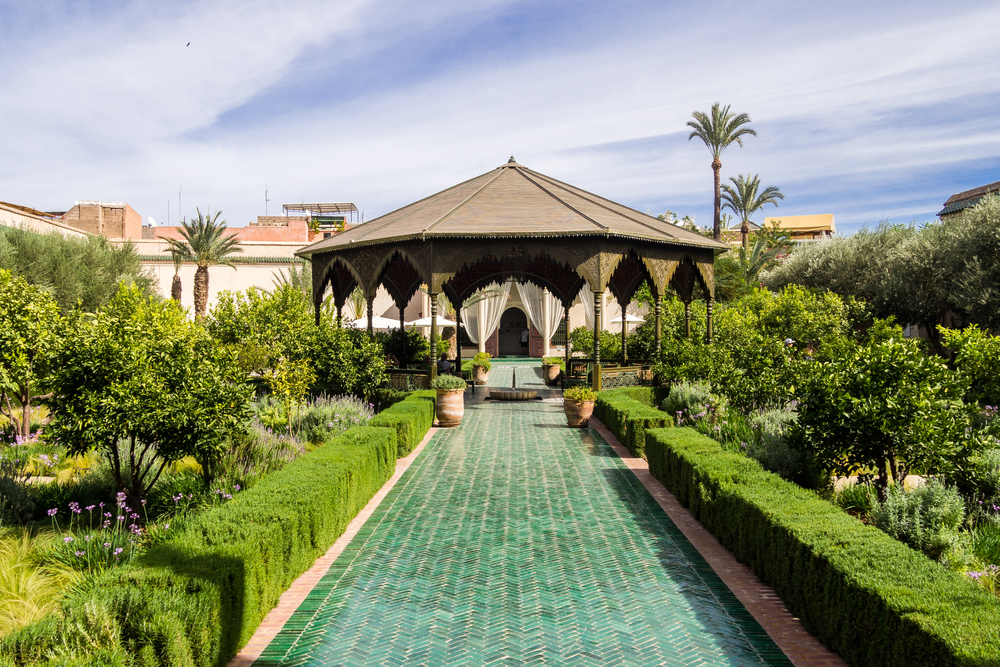 Le Jardin Secreto: A turquoise pond and ornate gardens with a gazebo in the background
