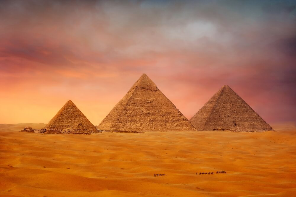 Tourist attractions of Egypt: three pyramids against a pink sunset