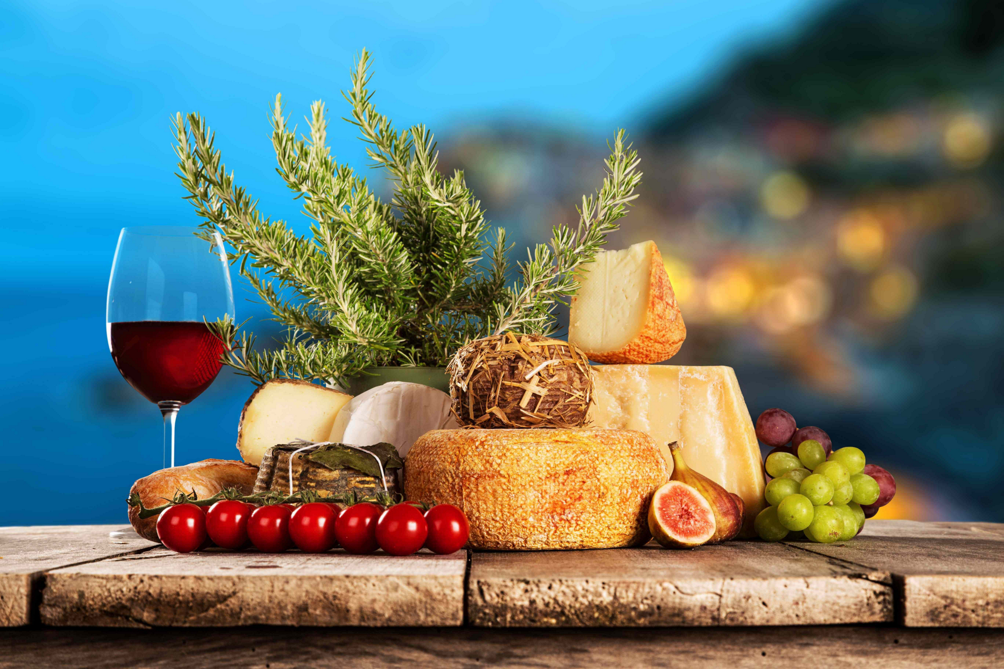 Traditionelle mediterrane Küche: Holztische mit Käse, Obst, Gemüse und einem Glas Wein.