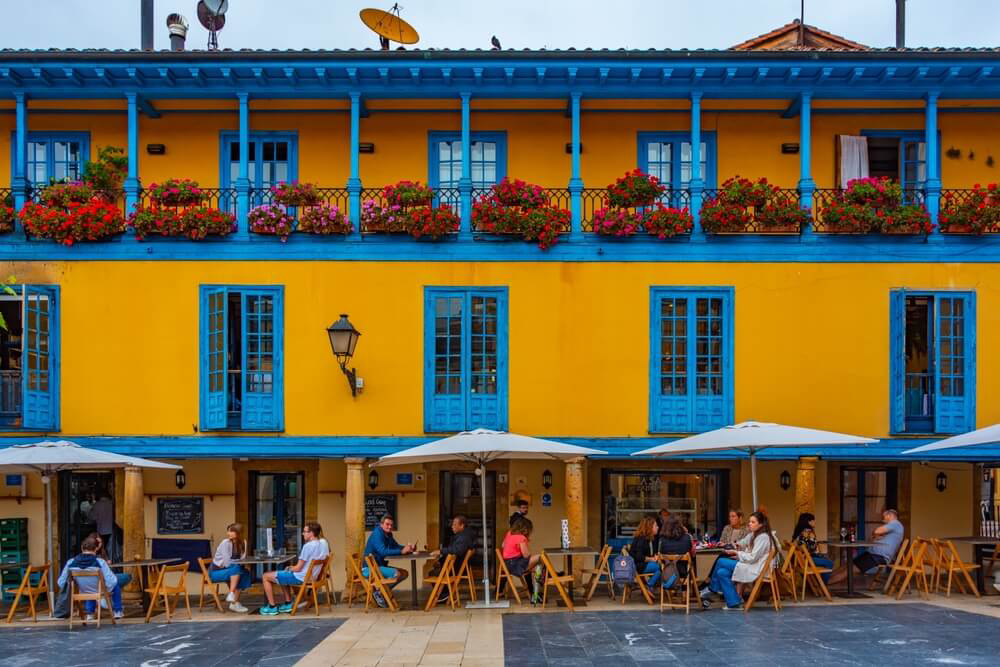 Oviedo: An orange and blue building with people sitting on the terrace 