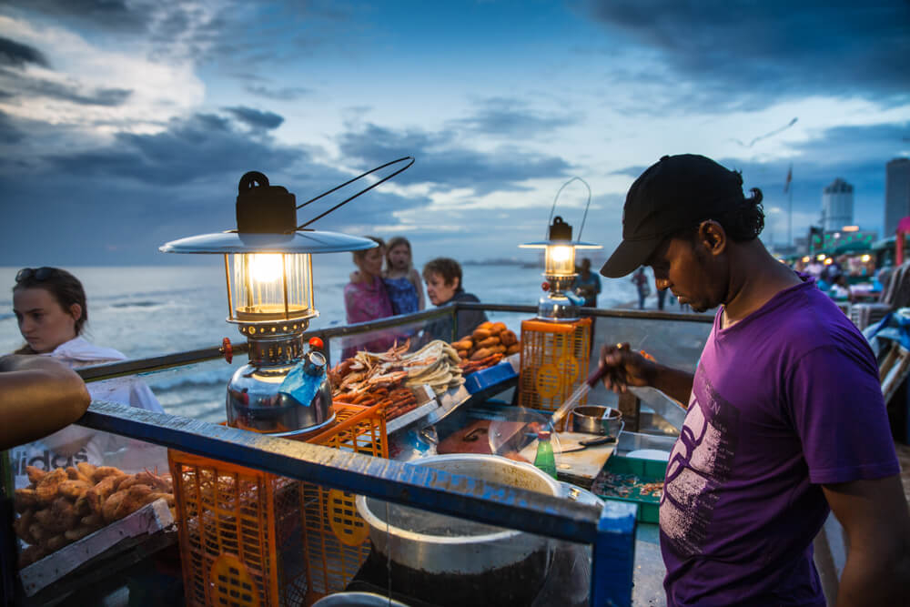Travel Trends: Local man cooking street food in Sri Lanka at night
