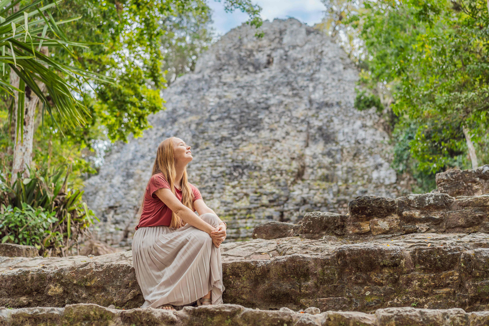 Frau sitzt auf Steinen in den Maya-Ruinen von Tulum.