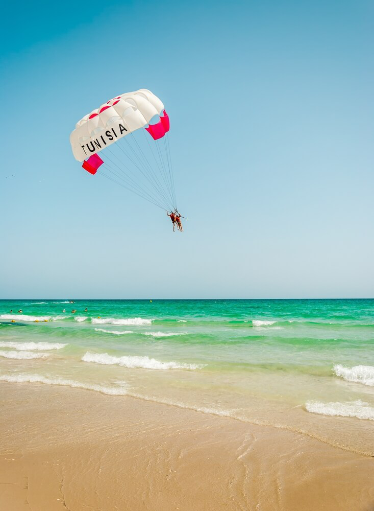 Parasailer mit dem Wort “Tunisia” an an einem tunesischen Strand.