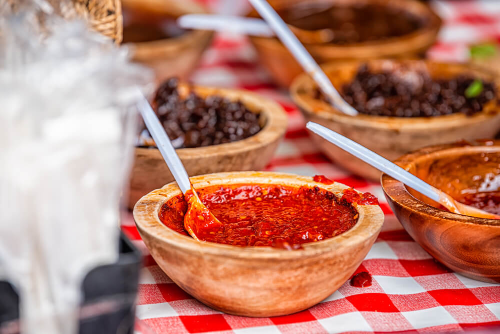 Tunisian harissa paste: A table with red and white tablecloth and wooden bowls of harissa