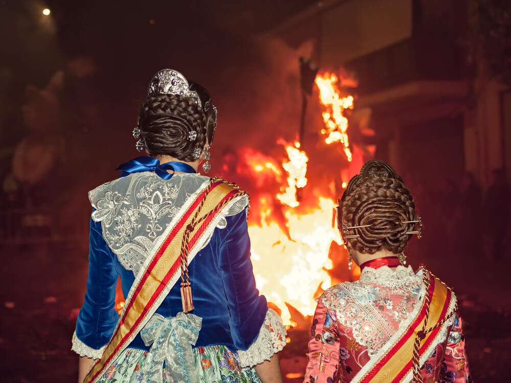 Unique experiences in Spain: two girls in traditional dress looking at a bonfire