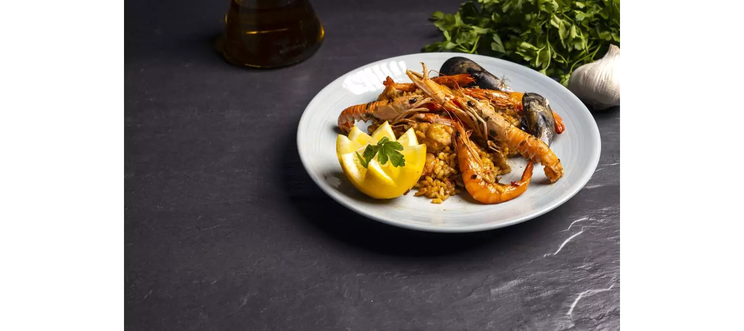 Eine echte valencianische Paella mit Paprika in einer Pfanne.