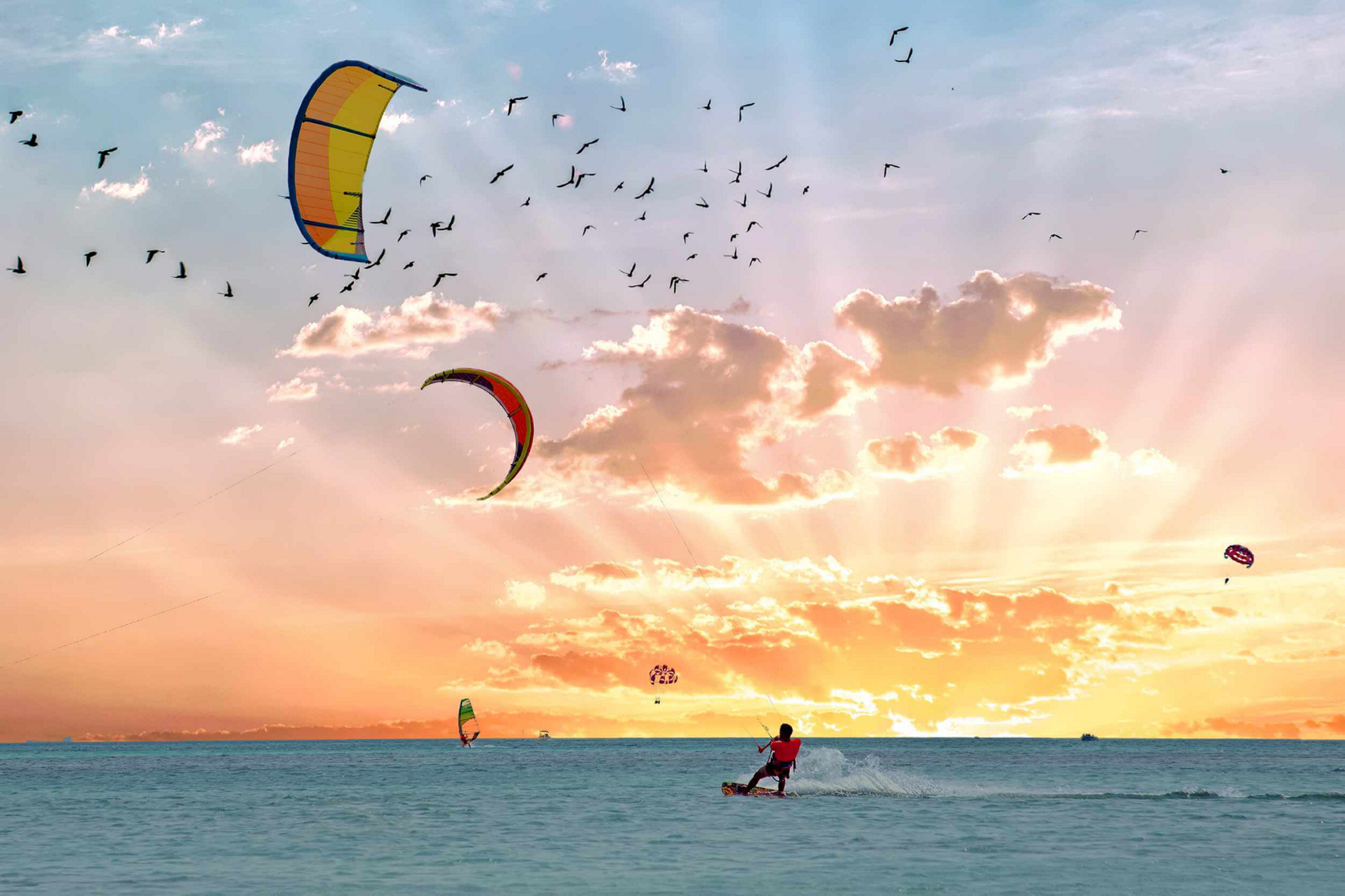 A man goes kite surfing at sunset, one of many water sports in Aruba.