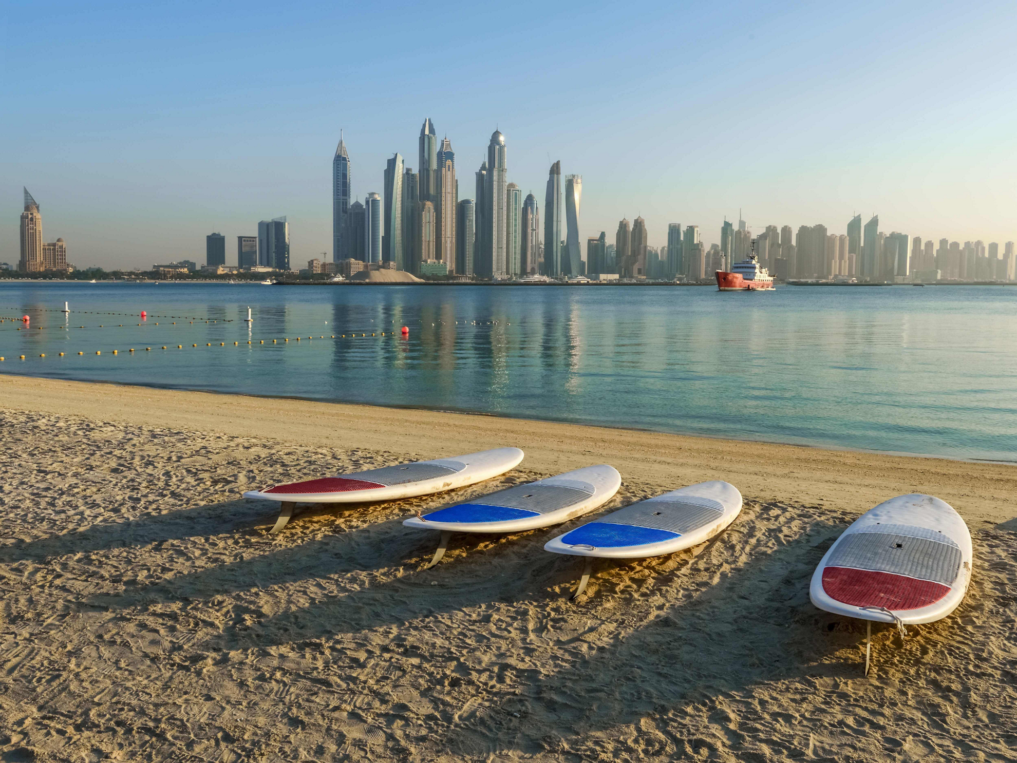 Water sports in Dubai: A white sand beach with blue sea and surfboards on the shore