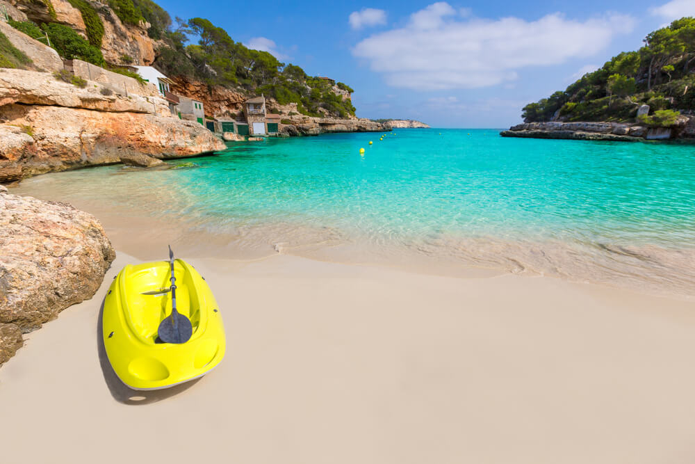 Watersports in Mallorca: Yellow kayak on golden sand with turquoise water in the background