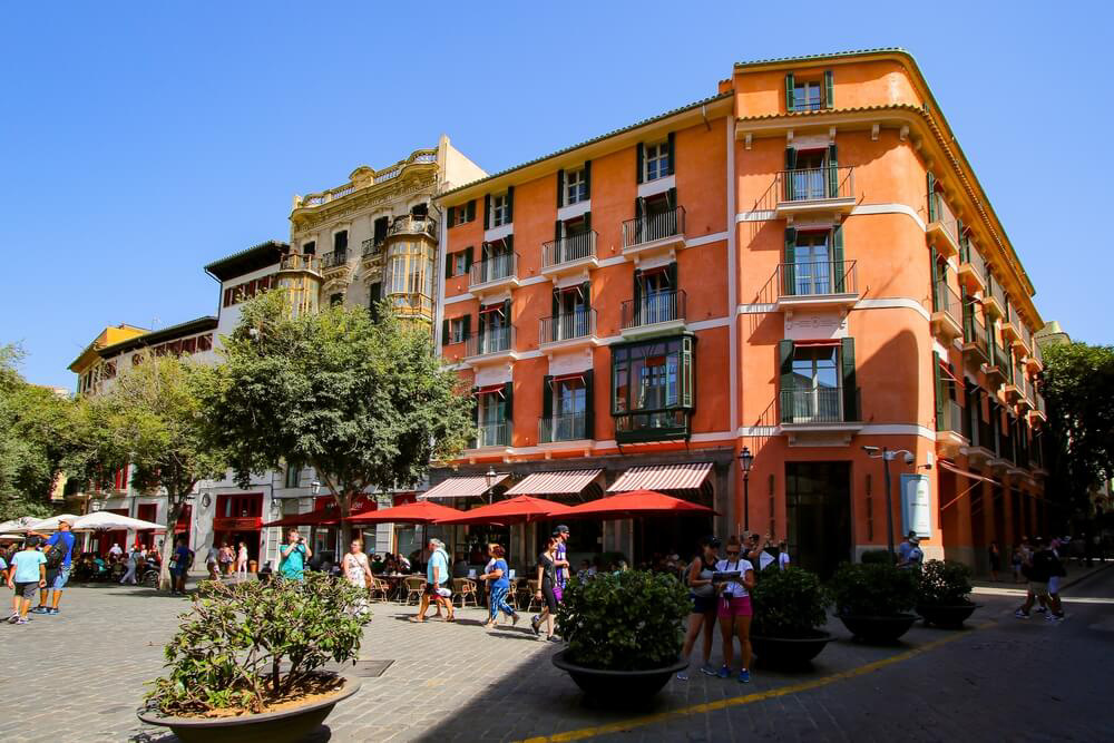 Weekend in Palma: A town square with a large orange building on the corner