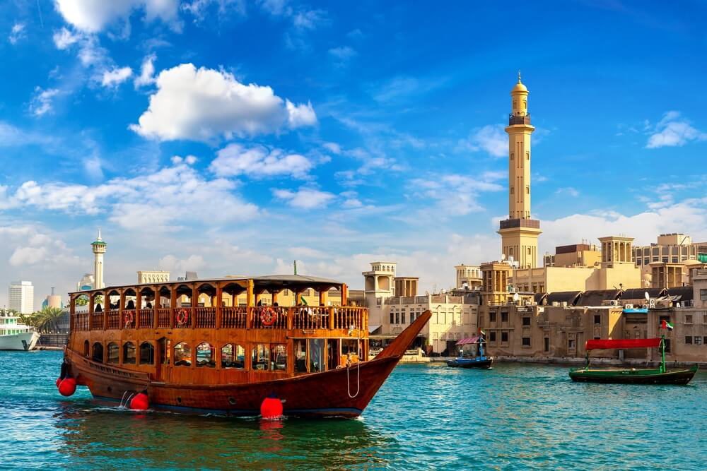 Dubai: A Dhow boat floating on the sea against the old Dubai skyline