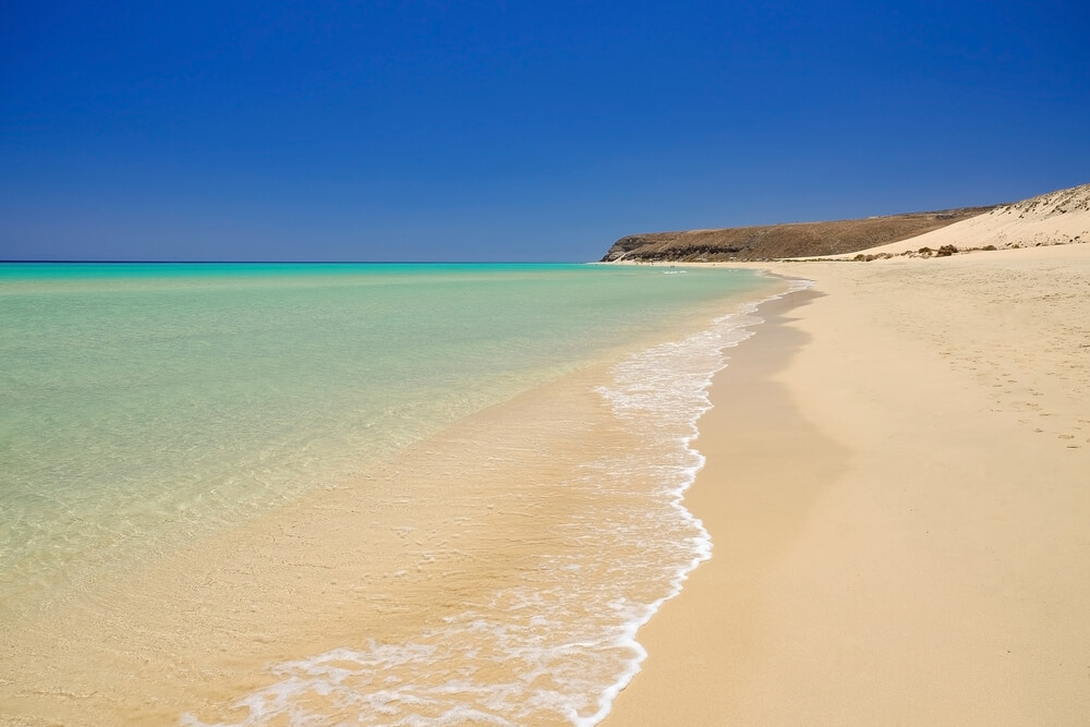 Winter Sun Destinations: A vast white sand beach with blue sky and sea