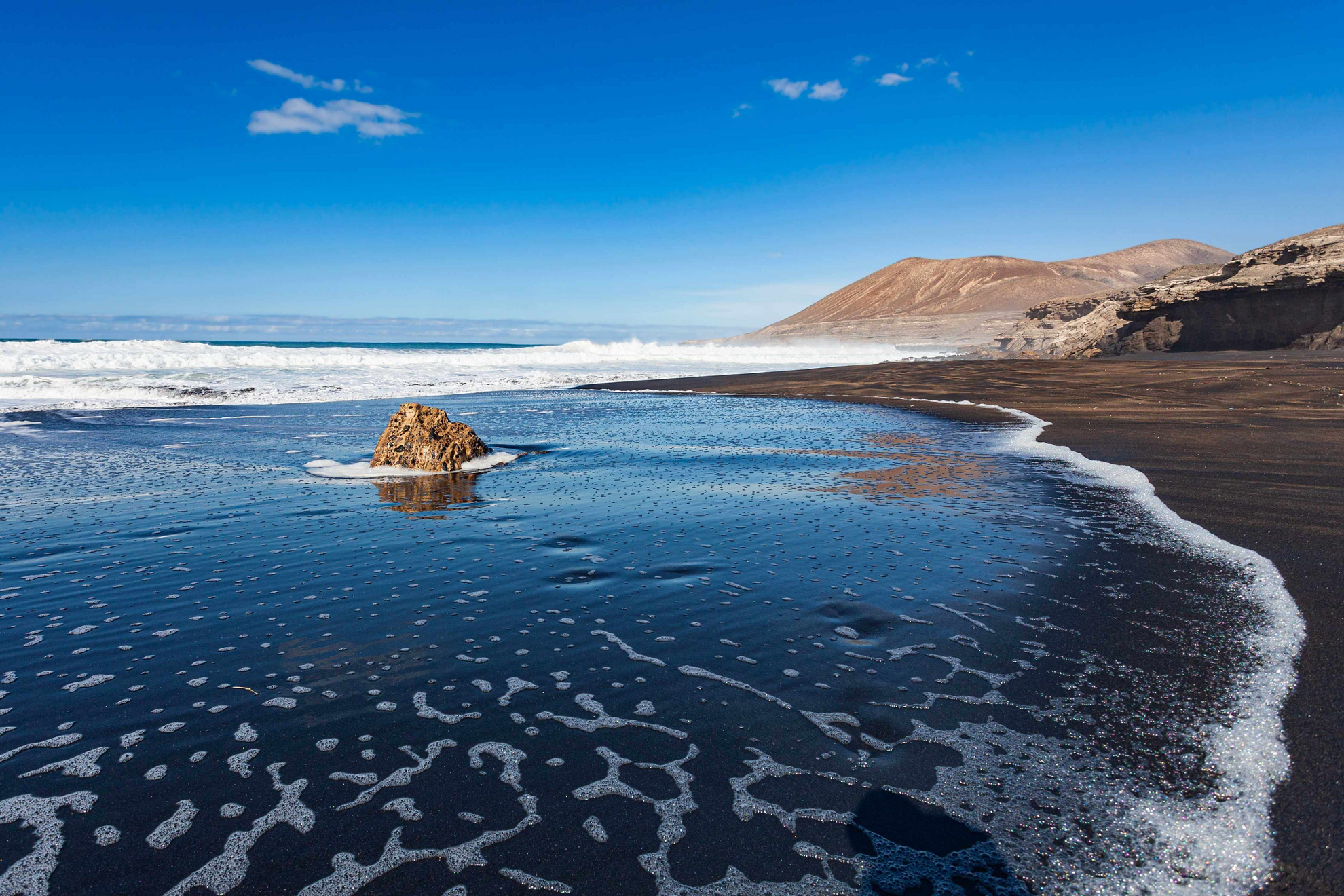 Winter Sun Destinations: A sunny black sand beach with nothing on it