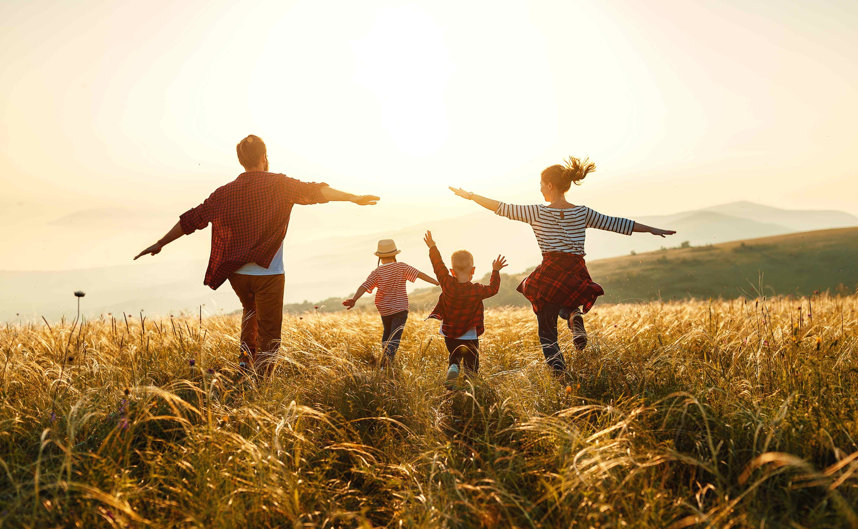 World Tourism Day: Family walking in a field holding hands