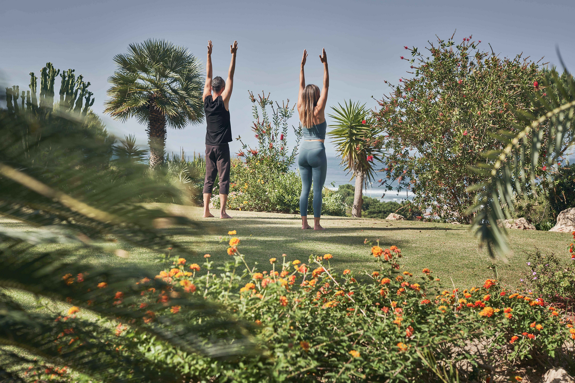 Yoga im Urlaub: ein Paar übt in einem Hotelgarten