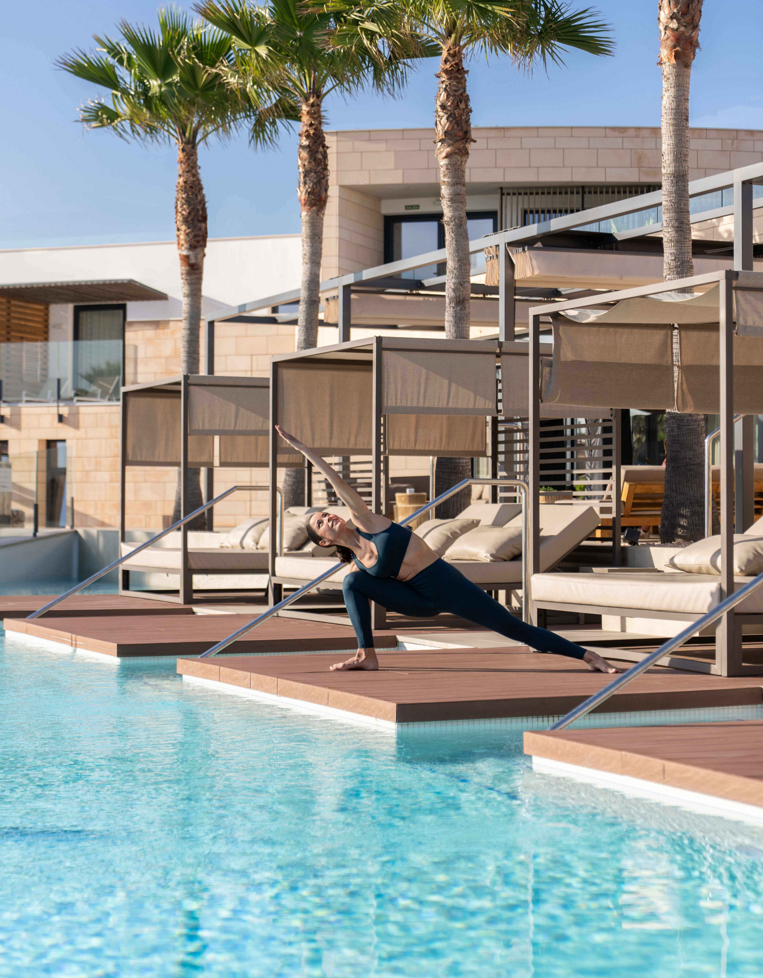 Yoga im Urlaub: eine Frau übt an einem Swimmingpool