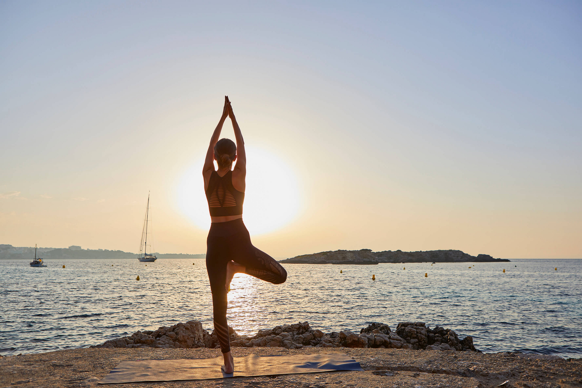 A woman practices yoga on a Spanish yoga retreat by the sea.