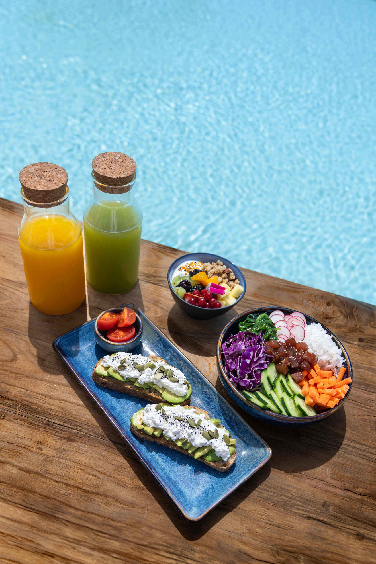 A tray of healthy yoga vacation food sits poolside.