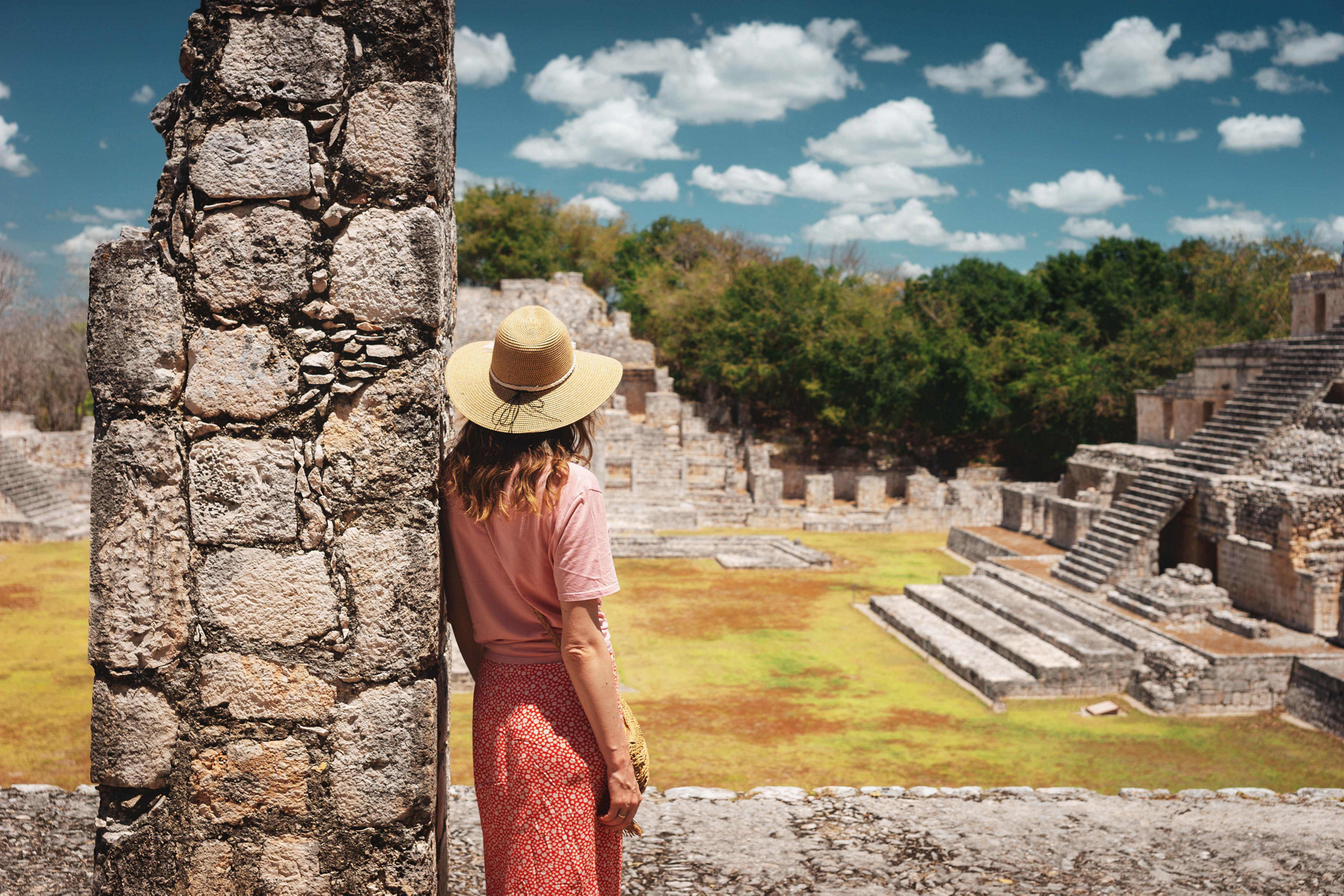 Yucatán Sehenswürdigkeiten: eine Touristin betrachtet alte Maya-Tempel.