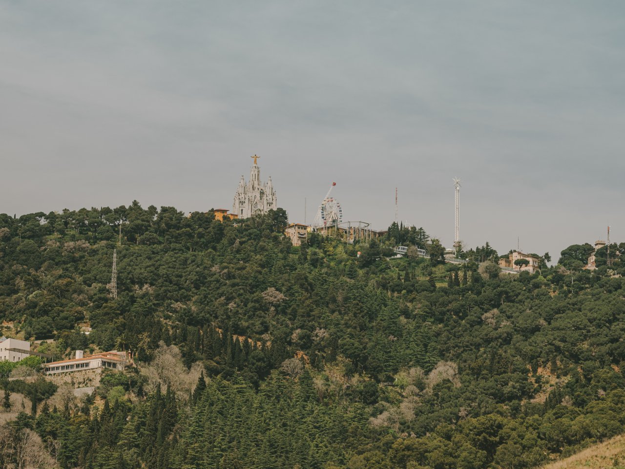 View of Tibidabo mountain with the Temple Expiatori del Sagrat Cor, the amusement park and abundant vegetation around it.
