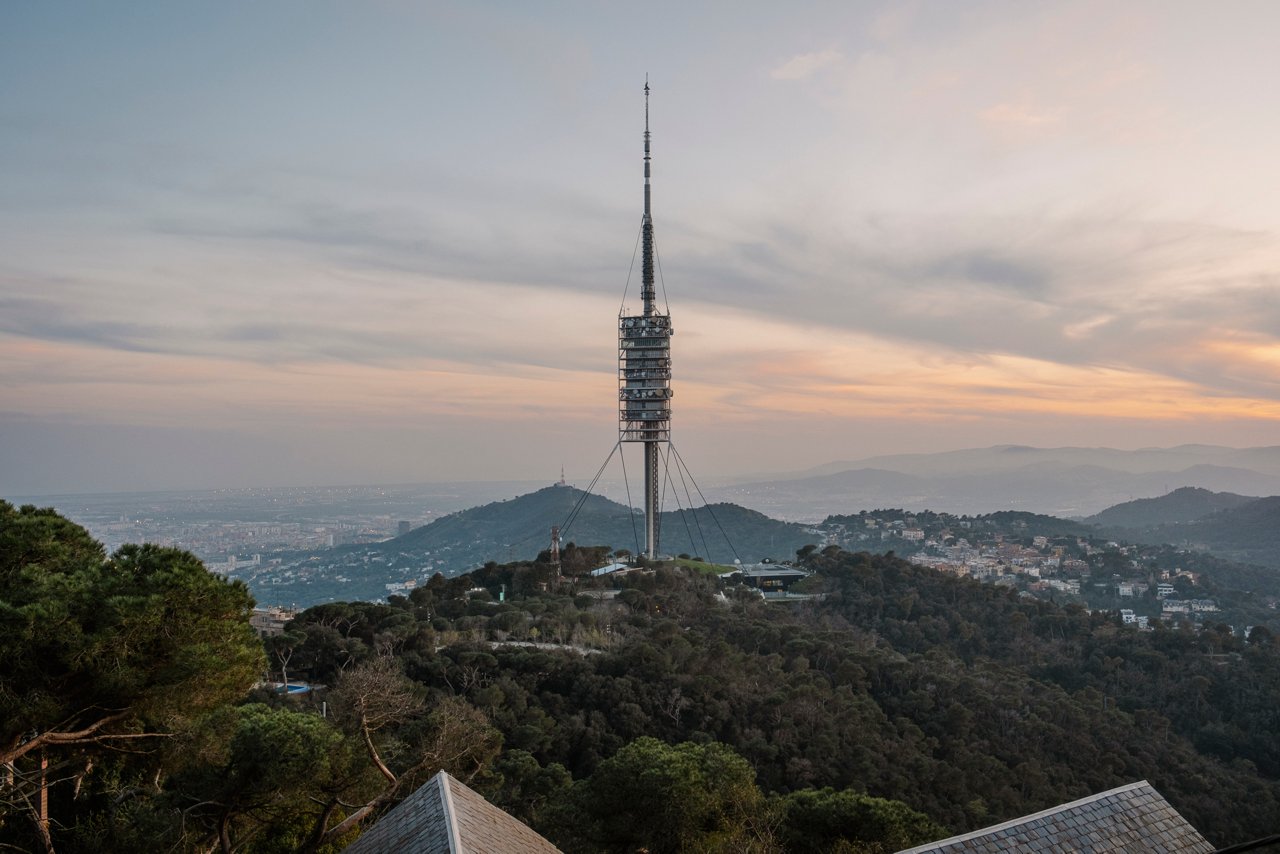 View of Tibidabo with the Collserola Tower at the center, surrounded by forest and with the city of Barcelona in the background at sunset