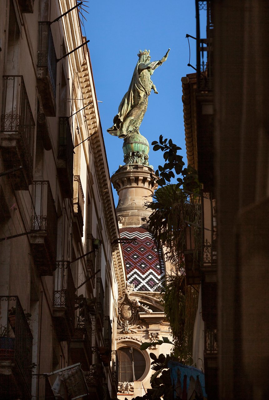 La figura de la Verge de la Mercè de perfil vist des d'un carrer estret
