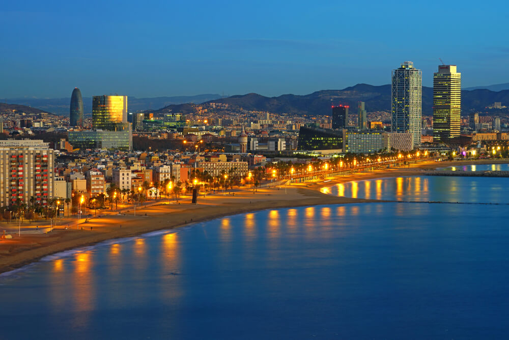 Barceloneta: The Barceloneta Beach lined with bars lit up at night 