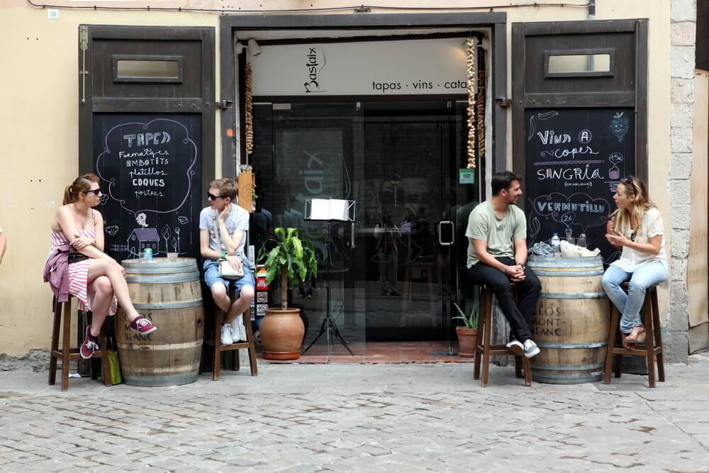 Poble Sec: An old tapas bar full of people with a wall of bottles behind the bar