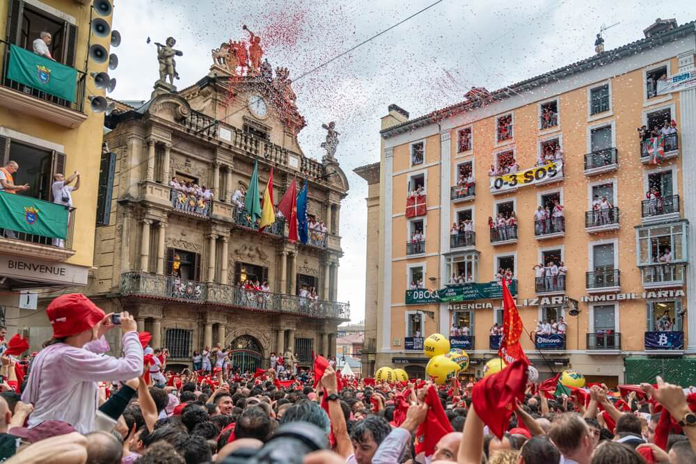 Pamplona: An old Spanish square full of people dressed in white and red