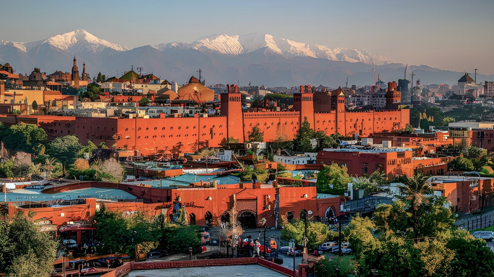 Marrakech: A large red building in the city with mountains in the background