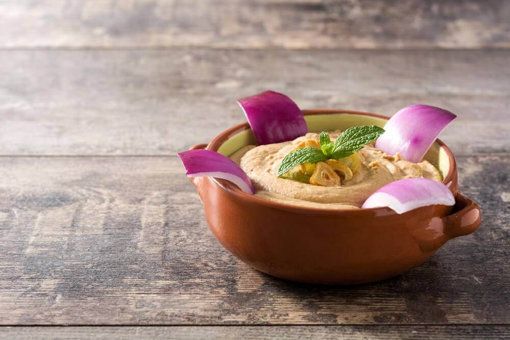 A bowl of escaldón de gofio served with red mojo sauce and white onion