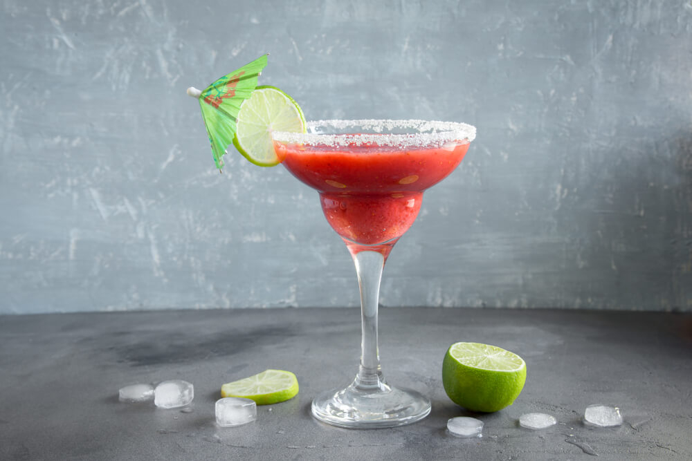 Daiquiri: A strawberry daiquiri on a grey surface with a lime slice and umbrella