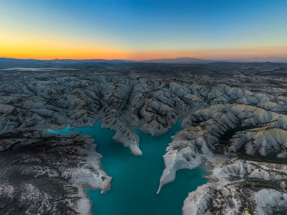 Zerklüftete Wüstenlandschaft mit türkisblauem Stausee in der Region Murcia.