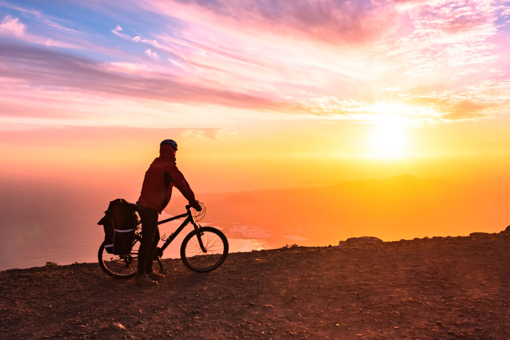 Cycling in Lanzarote: man with a bike on a mountain at sunset