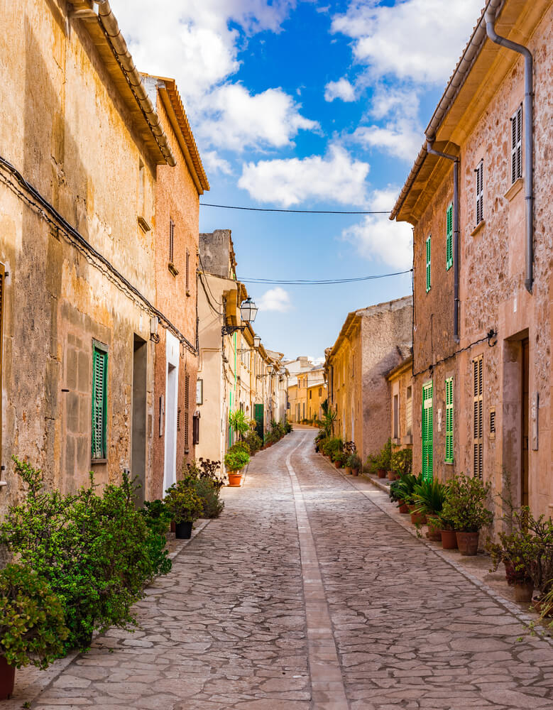 Lange Straße mit Kopfsteinpflaster im Dorf Petra auf Mallorca.